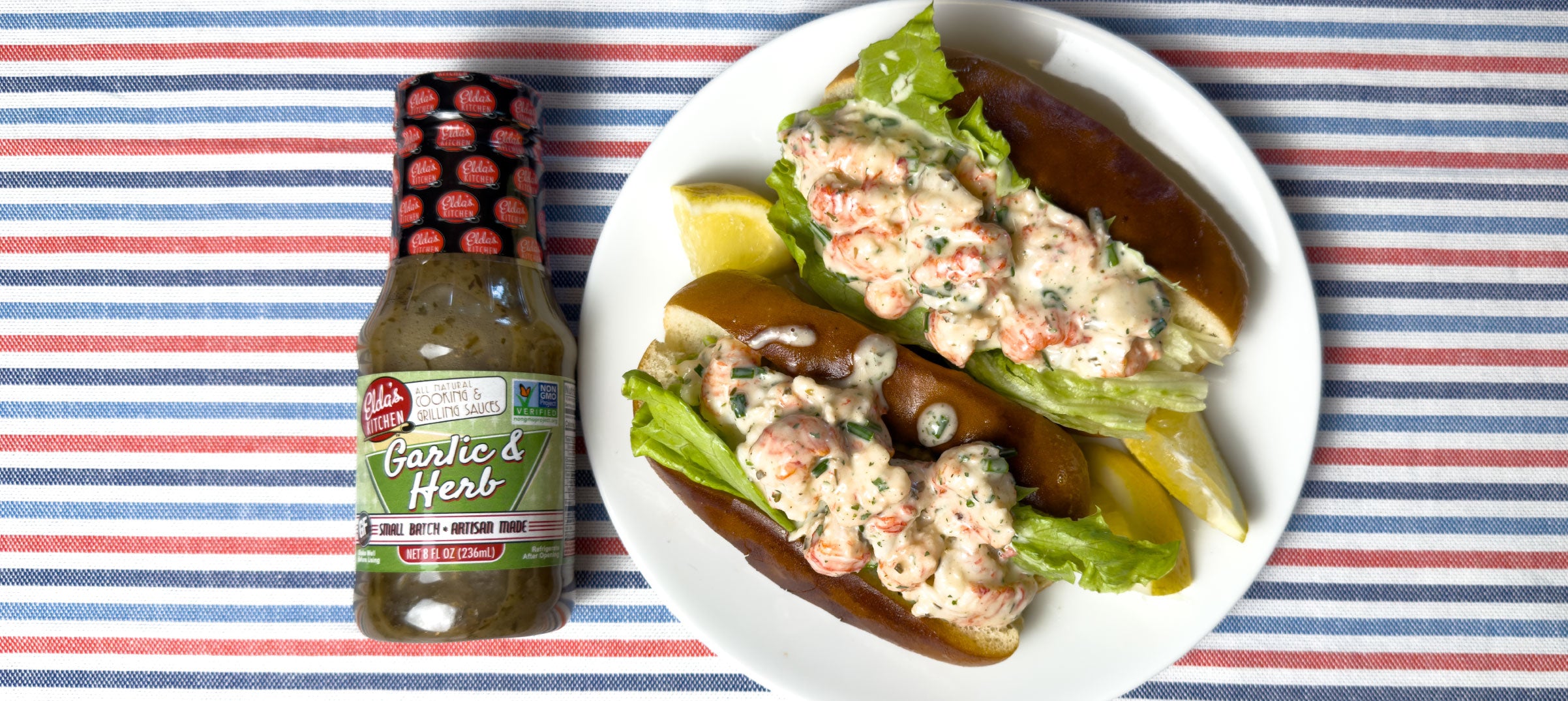 Creamy lobster filling on a hot dog buns with a bottle of Elda's Kitchen Garlic & Herb Sauce.