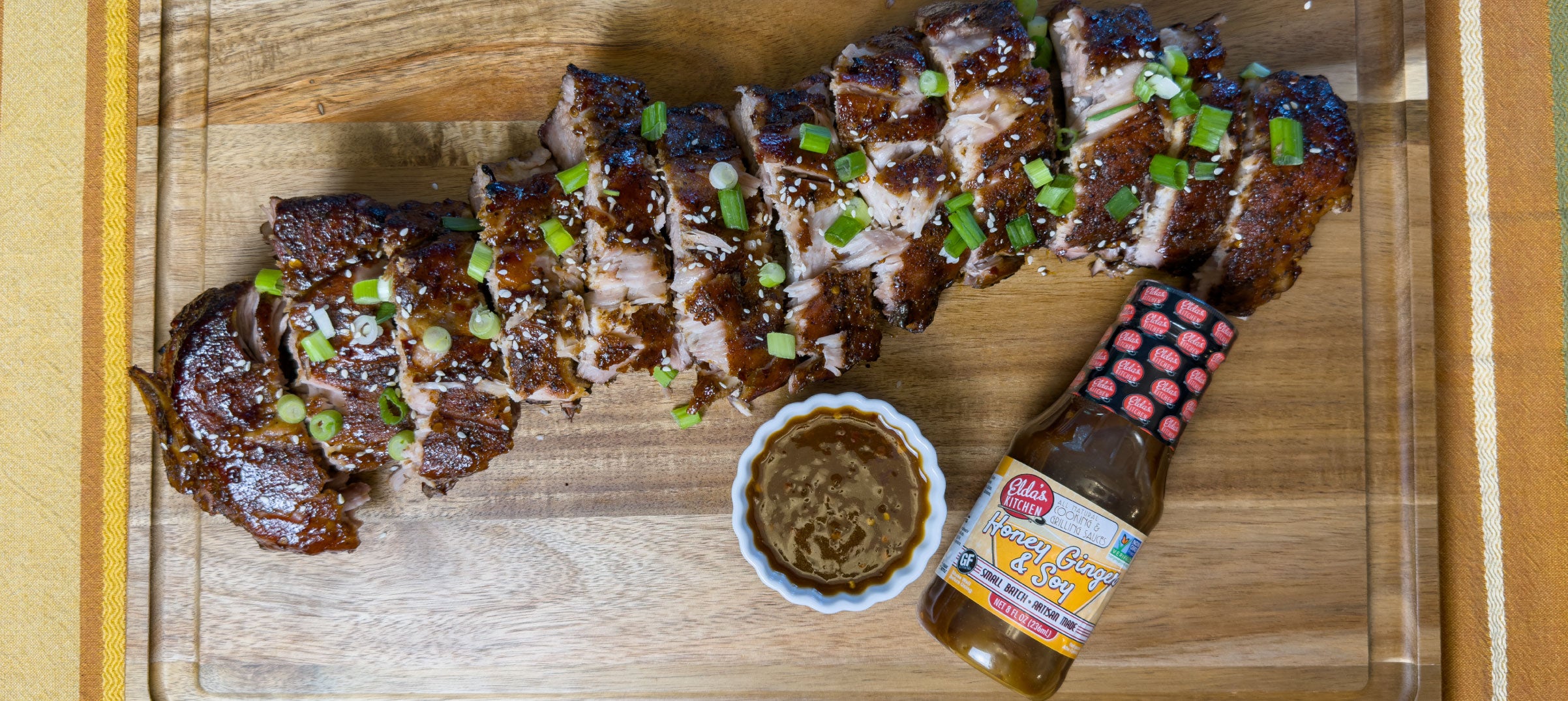 Glazed pork ribs with a bottle of Elda's Kitchen Honey Ginger & Soy Sauce